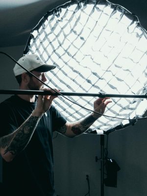 Cameraman adjusts lighting equipment on film set. Behind-the-scenes production view.