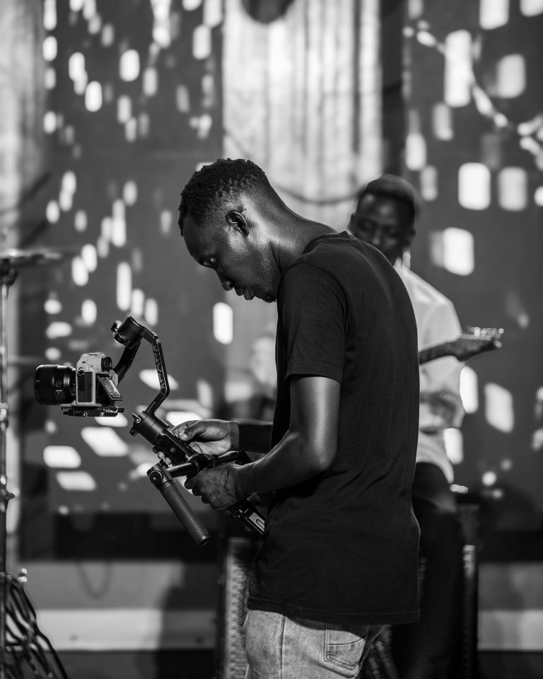 Candid black and white shot of a cameraman filming on set.